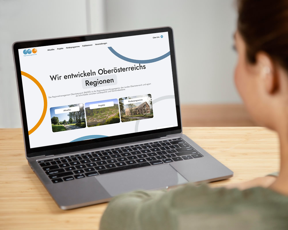 Home 21 Person schaut auf Laptop mit RMOÖ-Website am Bildschirm